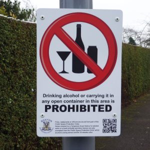 drinking alcohol or carrying it in any open container in this area is prohibited sign mounted to a lamppost