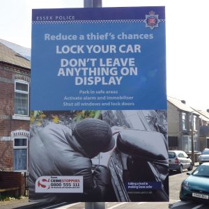 lamppost mounted sign informing public to lock your car & keep possessions out of view