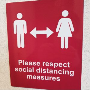 red sign informing people of social distancing measures in place