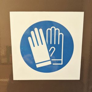 sticker showing gloves are needed in the following area