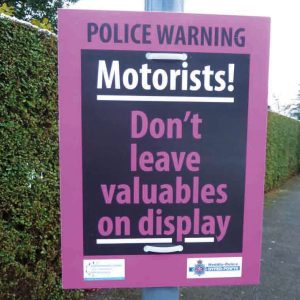 Pink & Black correx sign advising public to hide valuables from plain sight