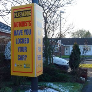 tri-ad sign attached to lamppost advising car users to lock their cars