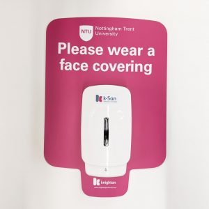 front view of a pink hand sanitising station mounted to a wall