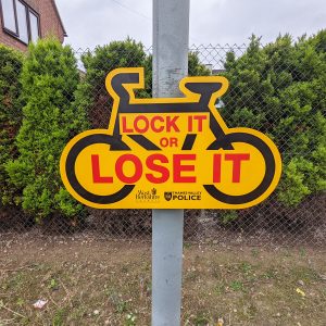 lock it or lose it sign in the shape of a bike mounted to a lamppost